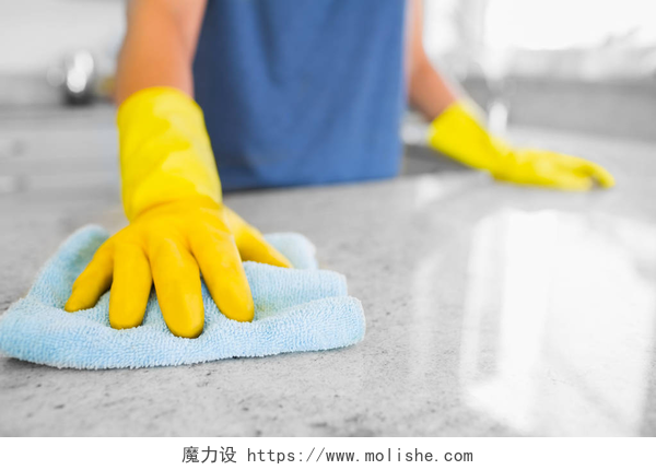 一个带着黄色手套清洁台面的人女人清洗厨房中的计数器